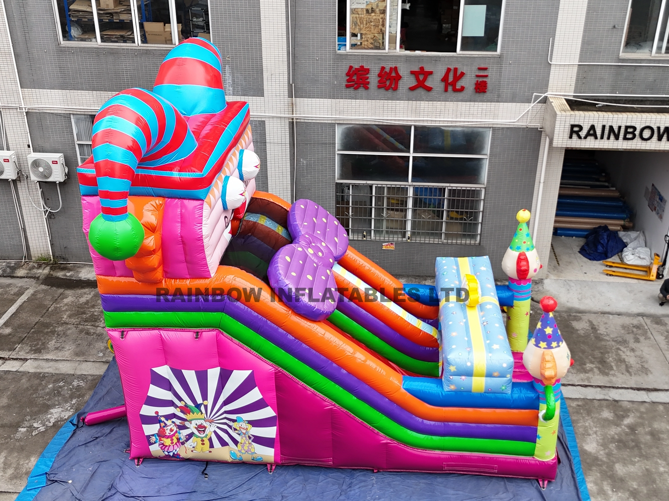 Giant Circus Theme Inflatable Slide with Clown Face Design, Rainbow Colors, and Tunnel Entrance